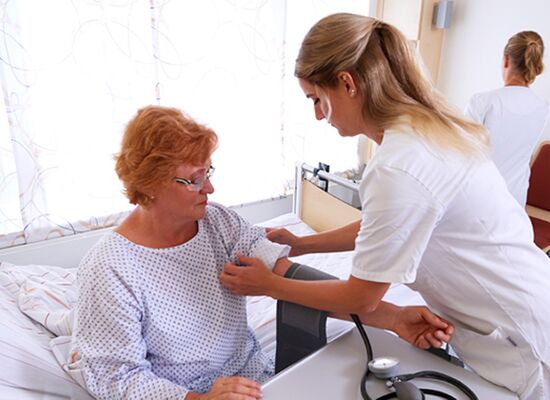 Foto: Mitarbeiterin kümmert sich um eine Patientin